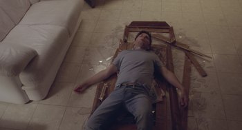 Movie still from “Flower” (2017), directed by Max Winkler – A man laying on the floor of a living room; Medium shot, High angle