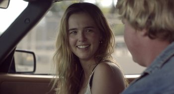 Movie still from “Flower” (2017), directed by Max Winkler – A young woman smiles brightly while sitting in a car; Close Up shot, Over the shoulder angle