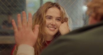 Movie still from “Flower” (2017), directed by Max Winkler – A woman with long hair is smiling and waving; Close Up shot, Over the shoulder angle