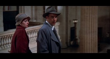 Movie still from “De Palma” (2015), directed by Jake Paltrow – A man in a hat and a suit standing next to a woman in a hat; Medium shot, Low angle