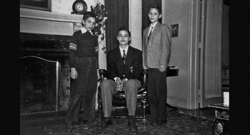 Movie still from “De Palma” (2015), directed by Jake Paltrow – A man sitting in a chair between two young boys; Wide shot, High angle