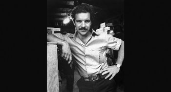 Movie still from “De Palma” (2015), directed by Jake Paltrow – A black and white photo of a man standing in a room; Medium shot, Low angle