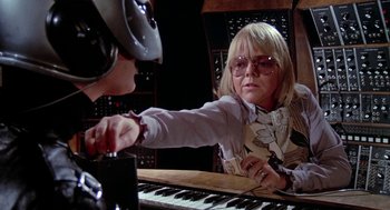 Movie still from “De Palma” (2015), directed by Jake Paltrow – An older woman and a younger man playing a musical instrument together; Medium shot, Over the shoulder angle