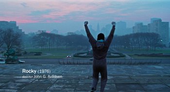 Movie still from “De Palma” (2015), directed by Jake Paltrow – A man standing on the side of a road with his arms in the air; Wide shot, Low angle