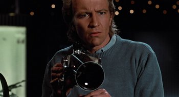 Movie still from “De Palma” (2015), directed by Jake Paltrow – A man holding a camera in front of a dark background; Close Up shot, Low angle