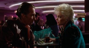 Movie still from “De Palma” (2015), directed by Jake Paltrow – A man and a woman sitting at a table with a drink; Medium shot, Low angle