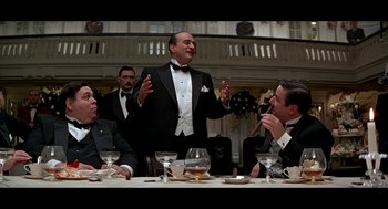 Movie still from “De Palma” (2015), directed by Jake Paltrow – A group of men sitting at a table in formal wear; Medium shot, Low angle