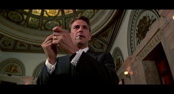 Movie still from “De Palma” (2015), directed by Jake Paltrow – A man in a suit and tie holding a cigarette; Medium shot, Low angle