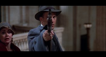 Movie still from “De Palma” (2015), directed by Jake Paltrow – A man in a hat and a suit holding a gun; Close Up shot, Low angle