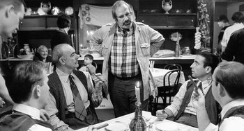 Movie still from “De Palma” (2015), directed by Jake Paltrow – A group of people sitting at a table; Medium shot, Over the shoulder angle