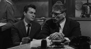 Movie still from “De Palma” (2015), directed by Jake Paltrow – Two men sitting at a table with a cup of coffee; Medium shot, Low angle