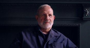 Movie still from “De Palma” (2015), directed by Jake Paltrow – An older man wearing a blue shirt is looking at the camera; Close Up shot, Low angle