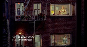 Movie still from “De Palma” (2015), directed by Jake Paltrow – A woman is sitting on a chair in the window of a brick building; Extreme Wide shot, Overhead angle