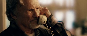 Movie still from “Deadfall” (2012), directed by Stefan Ruzowitzky – An older man talking on a phone while sitting down; Close Up shot, Low angle
