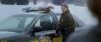 Movie still from “Deadfall” (2012), directed by Stefan Ruzowitzky – A woman standing next to a police car in the snow; Medium shot, Low angle