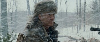 Movie still from “Deadfall” (2012), directed by Stefan Ruzowitzky – A man wearing a fur hat looking out of a window; Close Up shot, Low angle