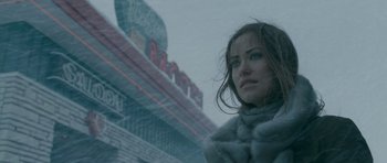 Movie still from “Deadfall” (2012), directed by Stefan Ruzowitzky – A woman standing in front of a building in the snow; Close Up shot, Over the shoulder angle