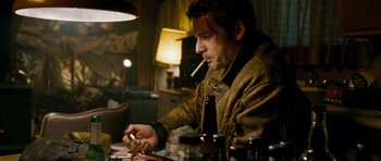 Movie still from “Deadfall” (2012), directed by Stefan Ruzowitzky – A man sitting at a table smoking a cigarette; Medium shot, High angle