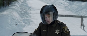 Movie still from “Deadfall” (2012), directed by Stefan Ruzowitzky – A woman in a police uniform with a motorcycle helmet on; Medium shot, Over the shoulder angle