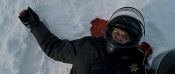 Movie still from “Deadfall” (2012), directed by Stefan Ruzowitzky – A man in a black jacket and a black helmet is standing in the snow; Close Up shot, Overhead angle