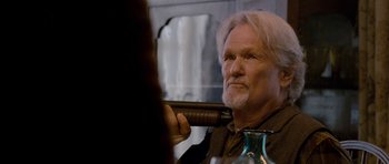 Movie still from “Deadfall” (2012), directed by Stefan Ruzowitzky – An older man with a long white beard holding a gun; Close Up shot, Over the shoulder angle