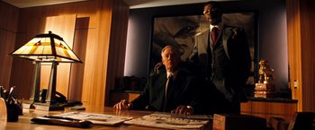 Movie still from “Deep Blue Sea” (1999), directed by Renny Harlin – A man sitting at a table in front of a picture; Medium shot, Over the shoulder angle