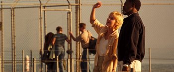 Movie still from “Deep Blue Sea” (1999), directed by Renny Harlin – A woman standing on top of a fence throwing a frisbee; Medium shot, Low angle