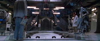Movie still from “Deep Blue Sea” (1999), directed by Renny Harlin – A man standing next to stairs in a building; Extreme Wide shot, High angle