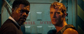 Movie still from “Deep Blue Sea” (1999), directed by Renny Harlin – Two men standing next to each other in front of a wall; Close Up shot, High angle