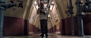 Movie still from “Deep Blue Sea” (1999), directed by Renny Harlin – A man standing in a hallway holding a cell phone to his ear; Wide shot, Low angle