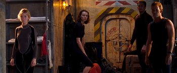 Movie still from “Deep Blue Sea” (1999), directed by Renny Harlin – A woman in a black dress leaning against a wall; Wide shot, Low angle