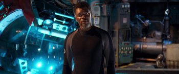 Movie still from “Deep Blue Sea” (1999), directed by Renny Harlin – A man in a black wetsuit standing in a room; Medium shot, Over the shoulder angle