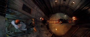Movie still from “Deep Blue Sea” (1999), directed by Renny Harlin – A man standing on top of a ladder in a building; Wide shot, Overhead angle