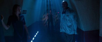 Movie still from “Deep Blue Sea” (1999), directed by Renny Harlin – A group of people standing in a dark room; Wide shot, Low angle