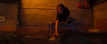 Movie still from “Deep Blue Sea” (1999), directed by Renny Harlin – A man leaning on a bench in a dark room; Medium shot, High angle