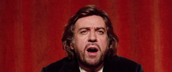 Movie still from “Deep Red” (1975), directed by Dario Argento – A person wearing a suit and tie; Close Up shot, Low angle