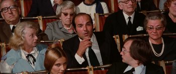 Movie still from “Deep Red” (1975), directed by Dario Argento – A group of people sitting in a row of chairs; Medium shot, High angle