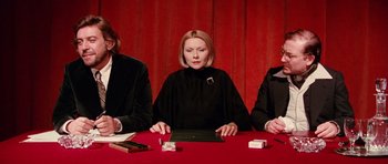 Movie still from “Deep Red” (1975), directed by Dario Argento – A woman sitting at a table with two other people; Medium shot, High angle