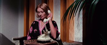 Movie still from “Deep Red” (1975), directed by Dario Argento – A woman is talking on a phone while sitting at a table; Medium shot, Low angle