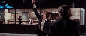 Movie still from “Deep Red” (1975), directed by Dario Argento – A man in a suit and tie holding up a drink; Medium shot, Low angle