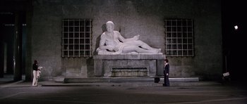 Movie still from “Deep Red” (1975), directed by Dario Argento – A man in a suit standing in front of a statue; Extreme Wide shot, High angle
