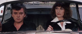 Movie still from “Deep Red” (1975), directed by Dario Argento – A man and a woman sitting in the back seat of a car; Close Up shot, Over the shoulder angle