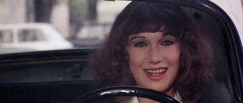Movie still from “Deep Red” (1975), directed by Dario Argento – A person in a car smiling at the camera; Close Up shot, High angle