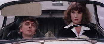 Movie still from “Deep Red” (1975), directed by Dario Argento – A man and a woman sitting in the back seat of a car; Close Up shot, Low angle