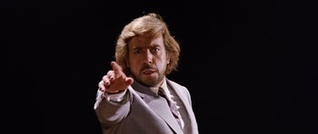 Movie still from “Deep Red” (1975), directed by Dario Argento – A man in a suit and tie pointing at the camera; Close Up shot, Low angle