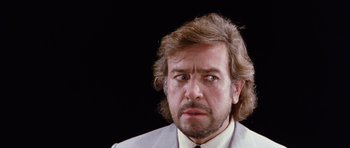 Movie still from “Deep Red” (1975), directed by Dario Argento – A person wearing a suit and tie; Close Up shot, Low angle