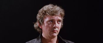 Movie still from “Deep Red” (1975), directed by Dario Argento – A person wearing a black shirt; Close Up shot, Low angle