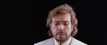 Movie still from “Deep Red” (1975), directed by Dario Argento – A person wearing a suit and tie; Close Up shot, Low angle