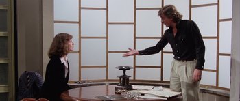 Movie still from “Deep Red” (1975), directed by Dario Argento – A man and a woman in front of a wooden table; Medium shot, Over the shoulder angle