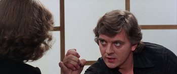 Movie still from “Deep Red” (1975), directed by Dario Argento – A man is holding his hand out to another man; Close Up shot, Over the shoulder angle